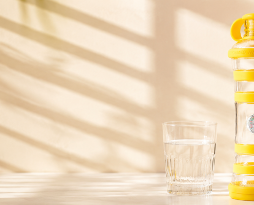 Bouteille i9 Solaire jaune et verre d’eau en période de canicule.